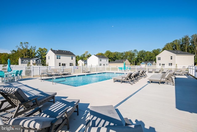 community pool featuring fence, a patio area, and a residential view
