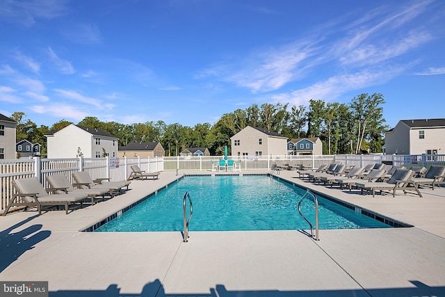 community pool with a patio, fence, and a residential view