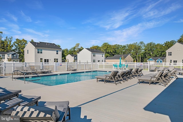 community pool featuring fence, a patio area, and a residential view