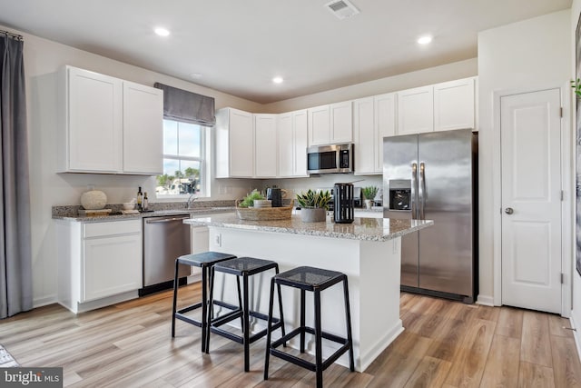 kitchen with white cabinetry, appliances with stainless steel finishes, visible vents, and a center island
