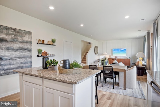 kitchen with open shelves, light stone countertops, light wood-style floors, open floor plan, and white cabinetry