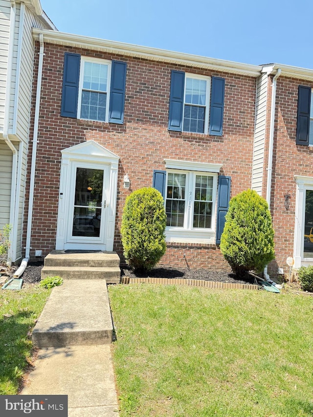 townhome / multi-family property with brick siding and a front yard