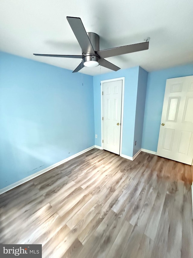 unfurnished bedroom with a ceiling fan, baseboards, and wood finished floors