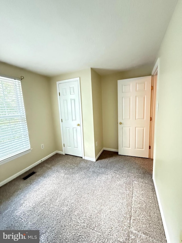 unfurnished bedroom with baseboards, carpet, and visible vents