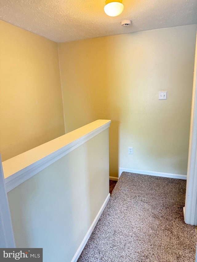 hall with baseboards, carpet, and a textured ceiling
