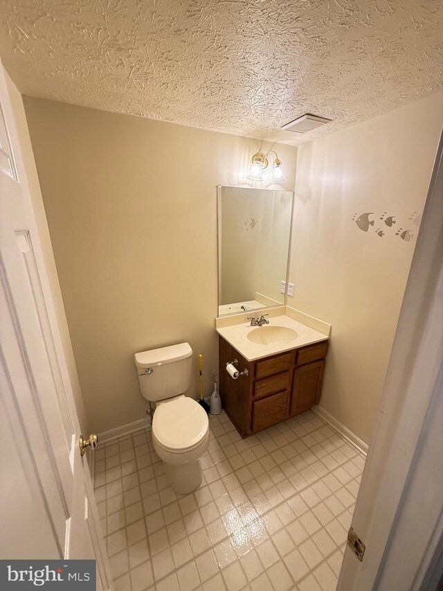 bathroom with toilet, a textured ceiling, tile patterned floors, and vanity