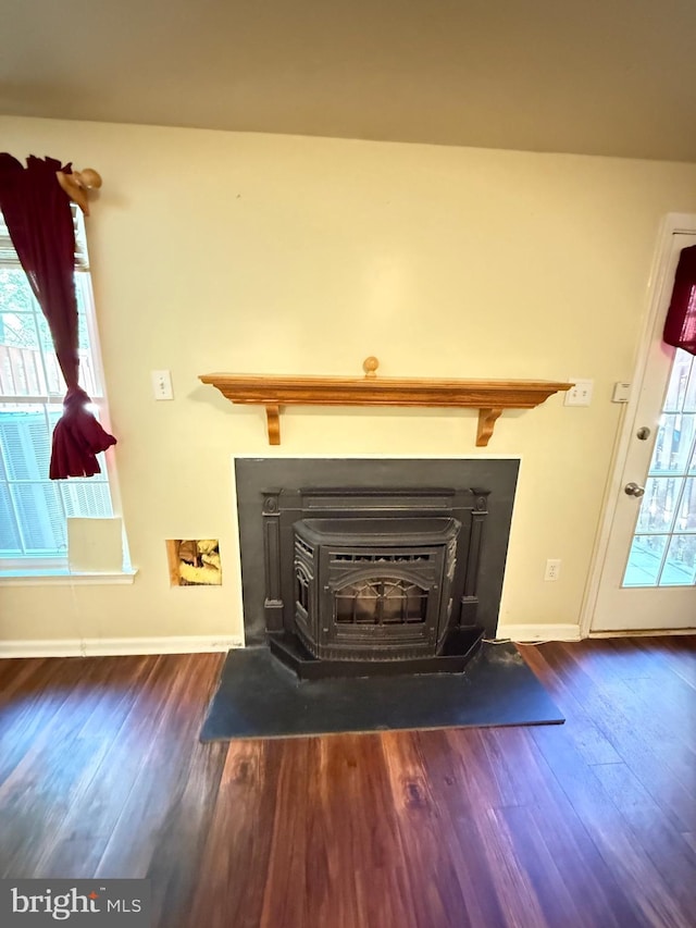 details with baseboards, a wood stove, and wood finished floors
