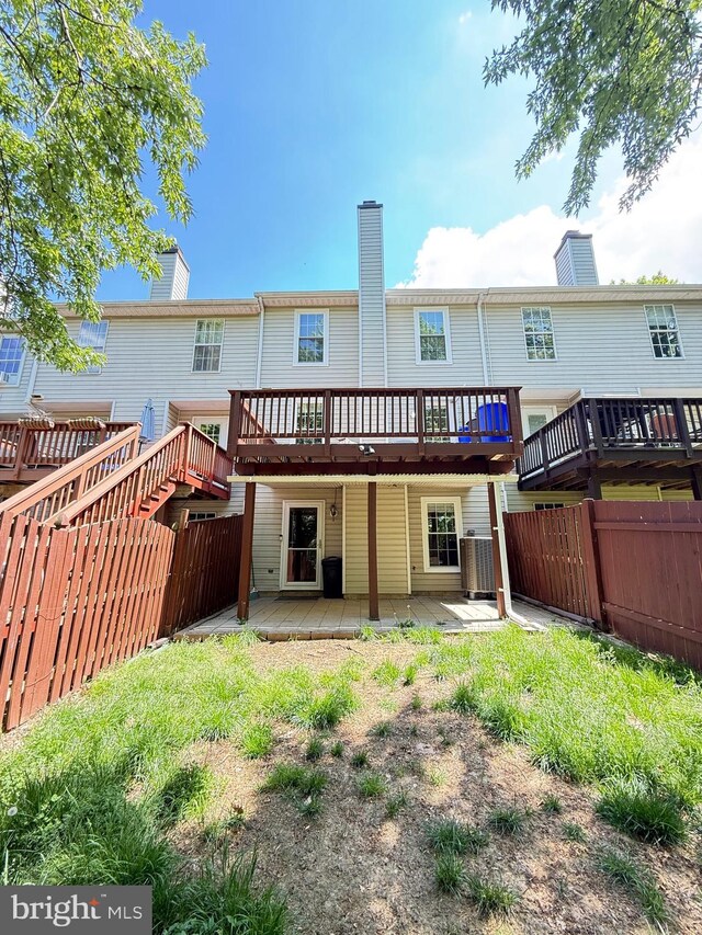 rear view of property featuring fence, a chimney, central AC, and a deck