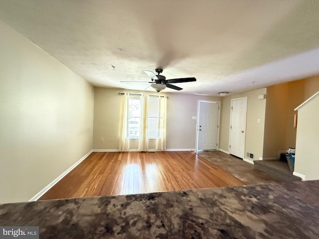spare room featuring baseboards, ceiling fan, wood finished floors, and visible vents