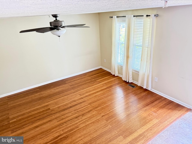 spare room featuring visible vents, a ceiling fan, light wood-style flooring, and a textured ceiling