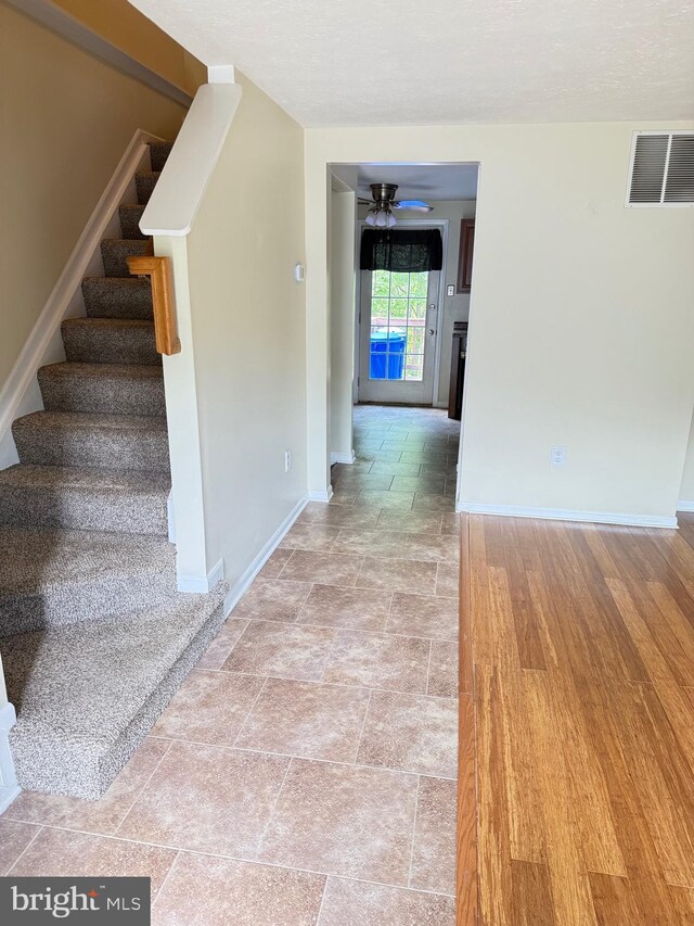 stairs with visible vents, baseboards, and ceiling fan