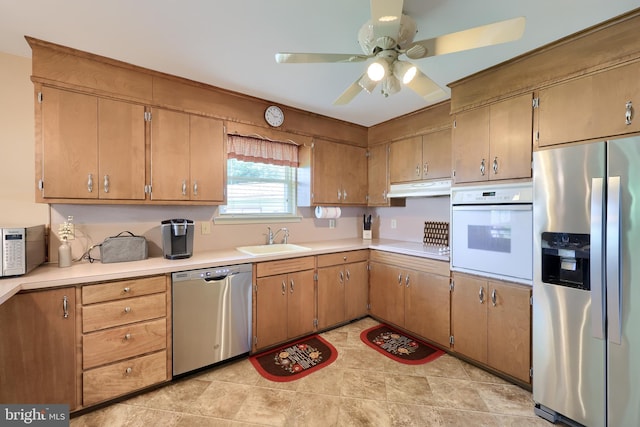 kitchen featuring a ceiling fan, appliances with stainless steel finishes, a sink, light countertops, and under cabinet range hood