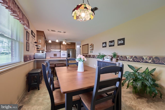 dining area with visible vents, a ceiling fan, stone finish flooring, and baseboards