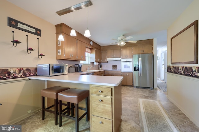 kitchen with a sink, light countertops, stainless steel appliances, a ceiling fan, and a peninsula