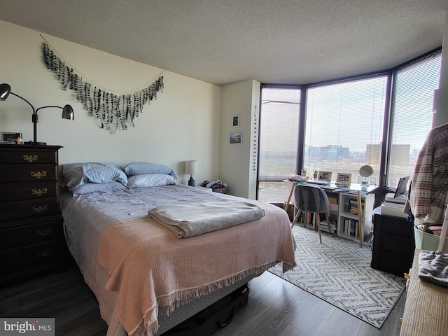 bedroom featuring a textured ceiling, wood finished floors, and a wall of windows