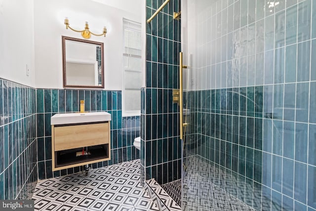 bathroom with toilet, tile walls, tiled shower, and vanity