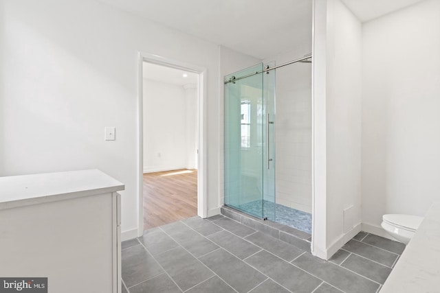 full bathroom with tile patterned flooring, baseboards, toilet, and a shower stall