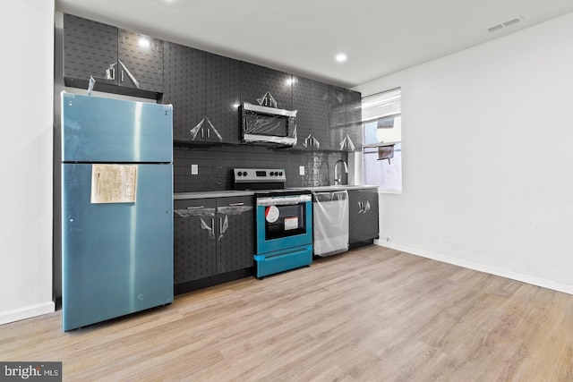 kitchen with baseboards, appliances with stainless steel finishes, light wood-style flooring, and visible vents