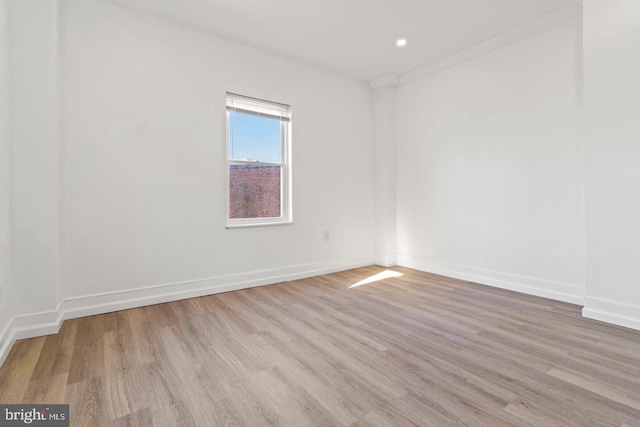 spare room featuring baseboards, recessed lighting, crown molding, and wood finished floors