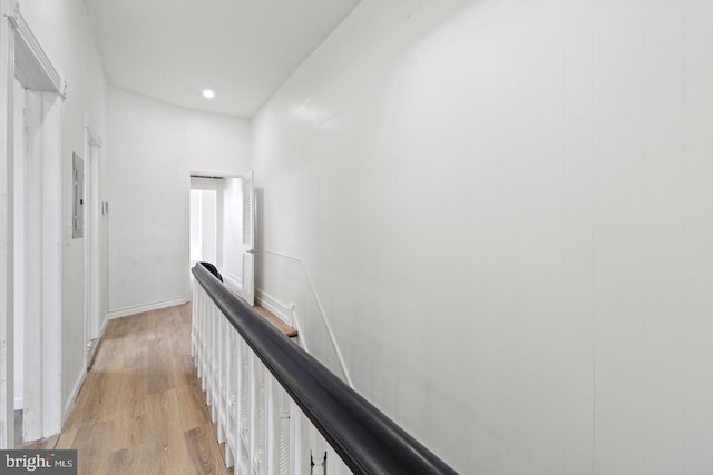 hallway featuring light wood-style floors, recessed lighting, electric panel, and an upstairs landing