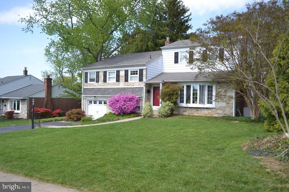 view of front of property with a garage, a front lawn, driveway, and stone siding