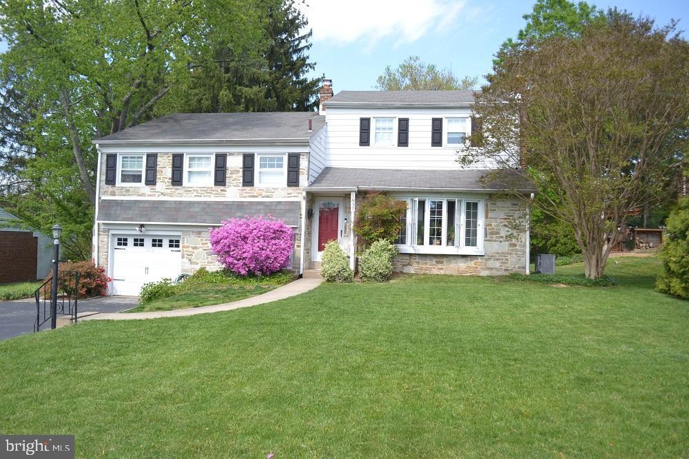 view of front of property with a chimney, a front yard, a garage, aphalt driveway, and stone siding
