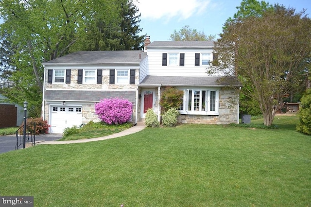 view of front of property with a chimney, a front yard, a garage, aphalt driveway, and stone siding