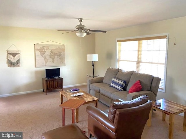 carpeted living area with a ceiling fan and baseboards