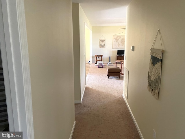 corridor featuring baseboards and carpet