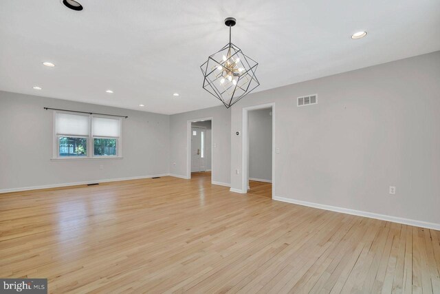 interior space with visible vents, light wood finished floors, baseboards, and a notable chandelier