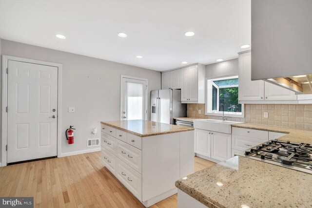 kitchen with a sink, backsplash, stainless steel appliances, and light wood finished floors
