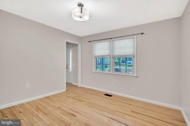 spare room with baseboards, visible vents, and wood finished floors