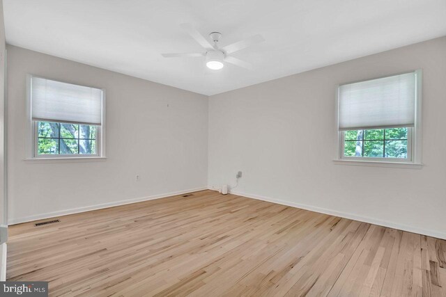 spare room featuring baseboards, wood finished floors, a wealth of natural light, and visible vents