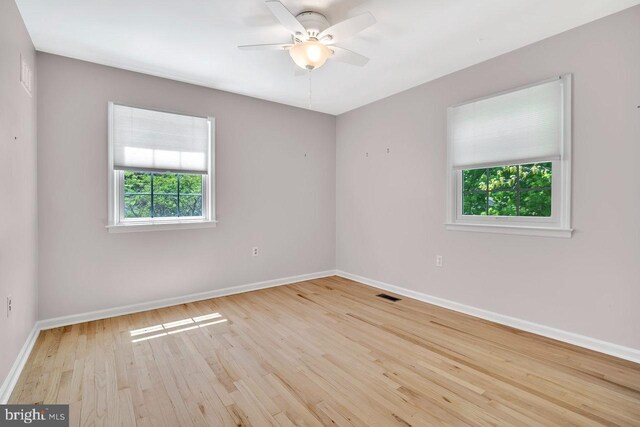 empty room featuring baseboards, a ceiling fan, wood finished floors, and visible vents