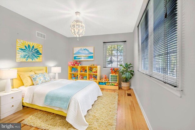 bedroom with a notable chandelier, baseboards, visible vents, and wood finished floors