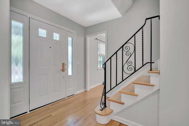 foyer entrance featuring baseboards, stairs, and wood finished floors