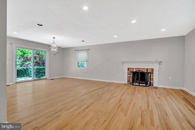 unfurnished living room with a fireplace, baseboards, light wood finished floors, a chandelier, and recessed lighting
