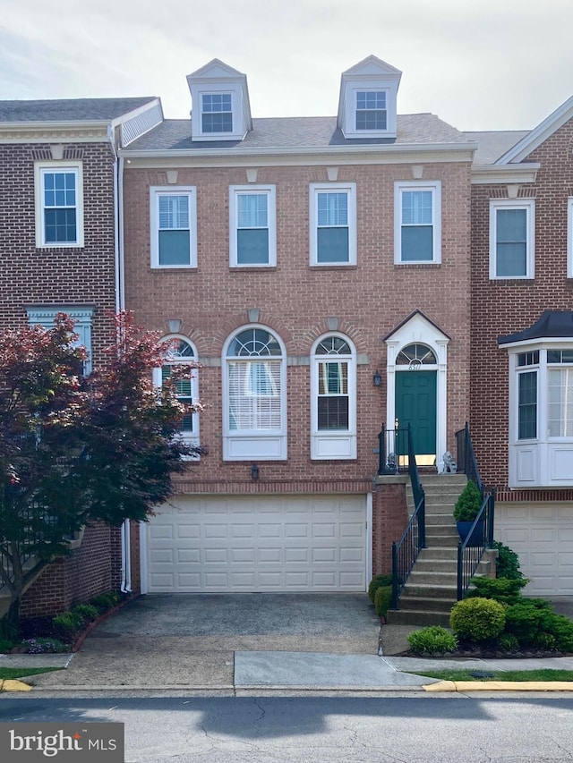 townhome / multi-family property featuring brick siding, a garage, and driveway