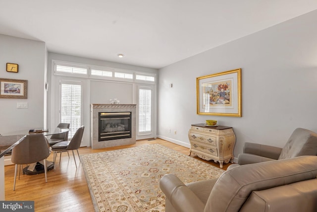 living room with light wood-style floors, baseboards, and a high end fireplace