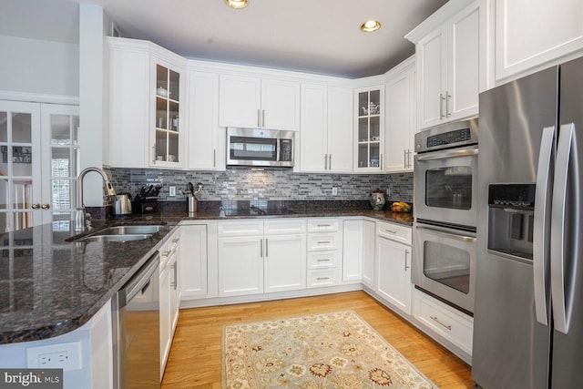 kitchen featuring white cabinetry, stainless steel appliances, light wood-style flooring, and a sink