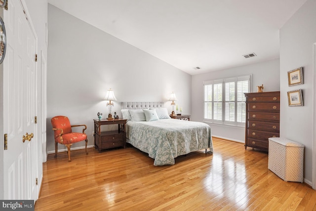 bedroom with light wood finished floors, baseboards, and lofted ceiling