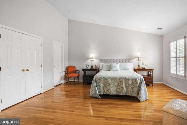 bedroom featuring baseboards, lofted ceiling, light wood finished floors, and visible vents