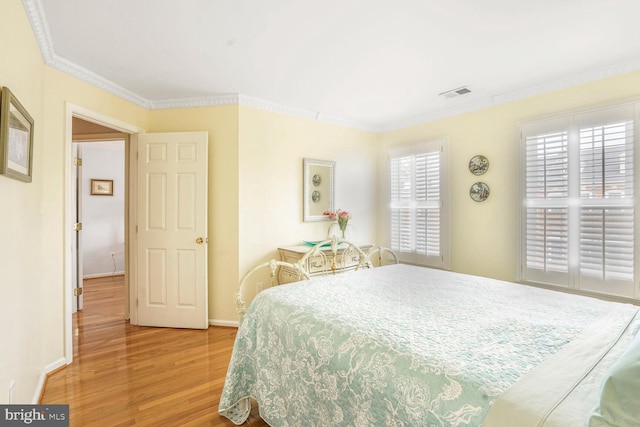 bedroom featuring crown molding, visible vents, wood finished floors, and baseboards