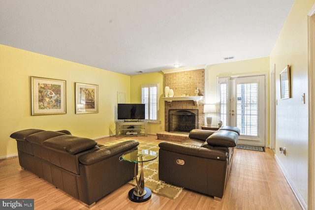 living area with baseboards, light wood-style floors, a fireplace, and visible vents