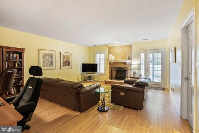living area featuring light wood finished floors, plenty of natural light, visible vents, and a fireplace