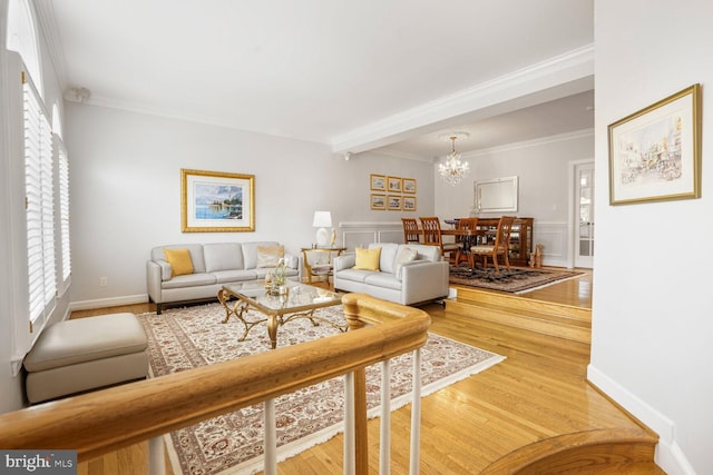 living room with ornamental molding, a notable chandelier, and light wood-style floors