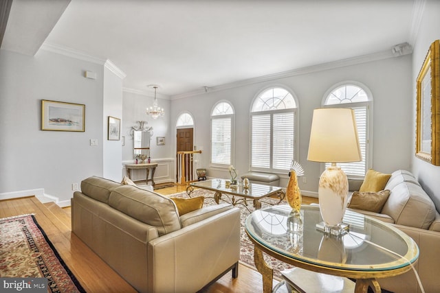 living room with light wood-style floors, a chandelier, baseboards, and ornamental molding