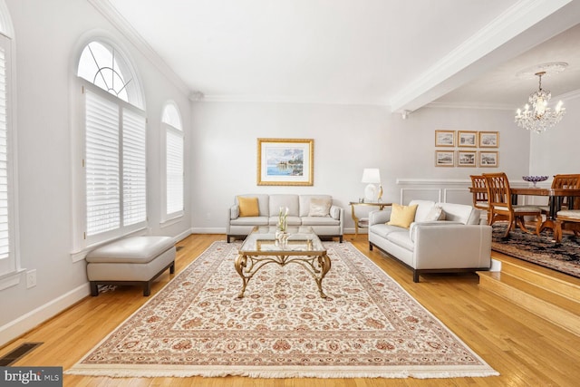 living area with baseboards, ornamental molding, light wood finished floors, visible vents, and a chandelier