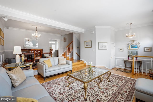 living area featuring stairway, an inviting chandelier, ornamental molding, and wood finished floors