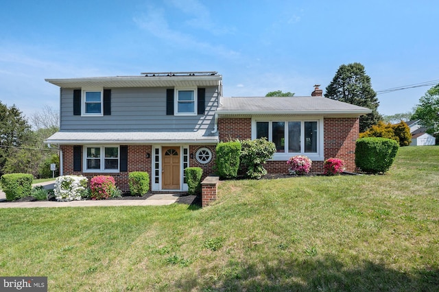 split level home with brick siding, a chimney, and a front yard